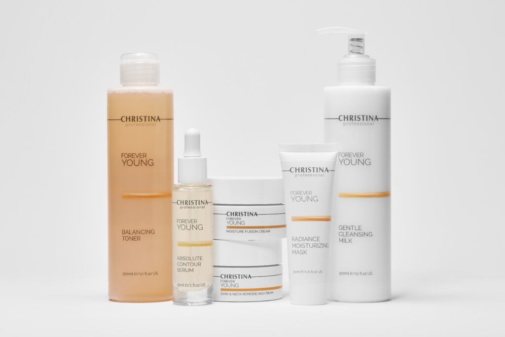 Christina professional skincare lineup on a white background featuring Balancing Toner orange bottle and various white tubes and jars